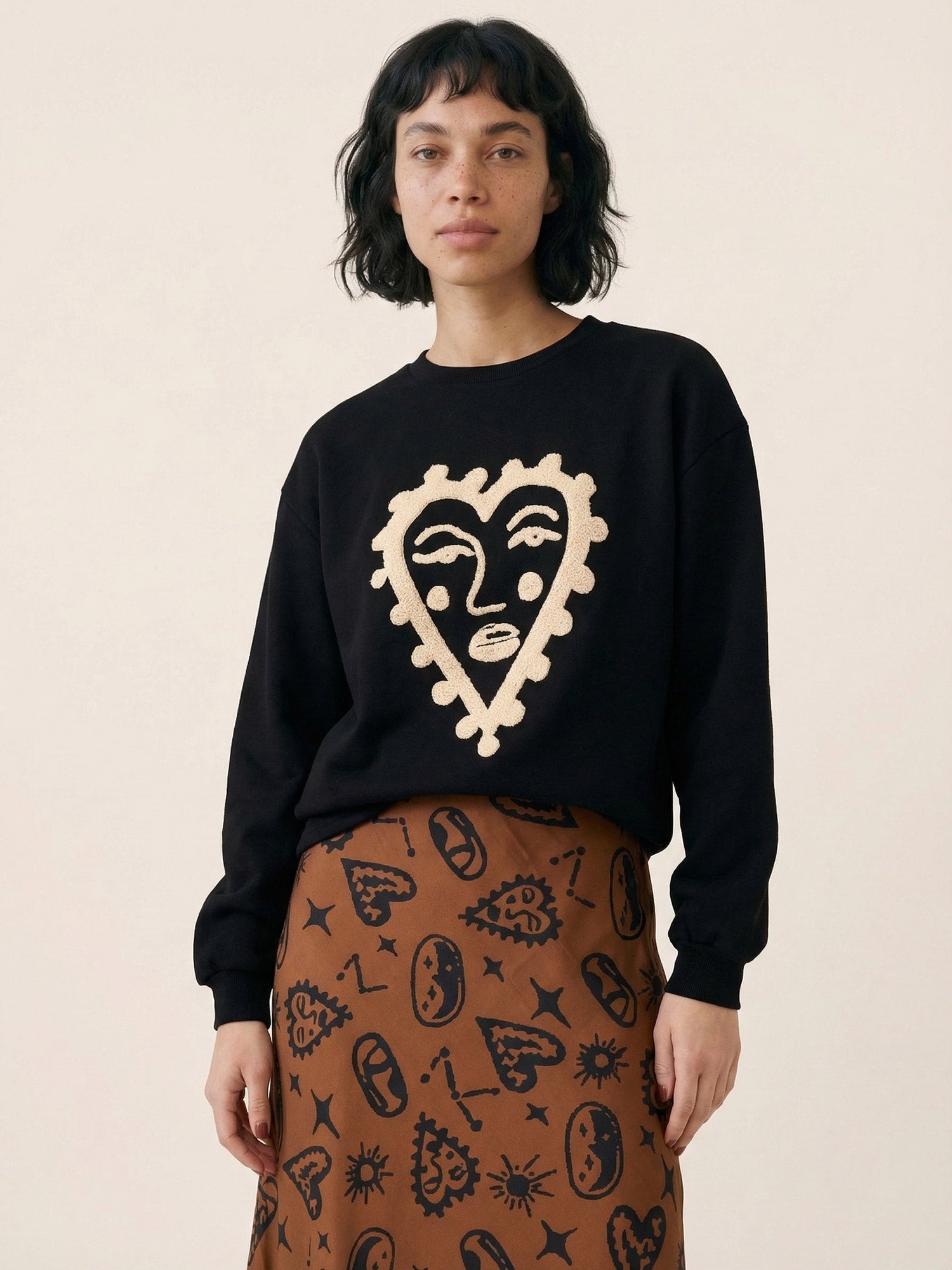 Sudadera de punto negra con rostro enmarcado en un corazón rizado crema de Pepaloves en Tiendas Via Vai Estepona