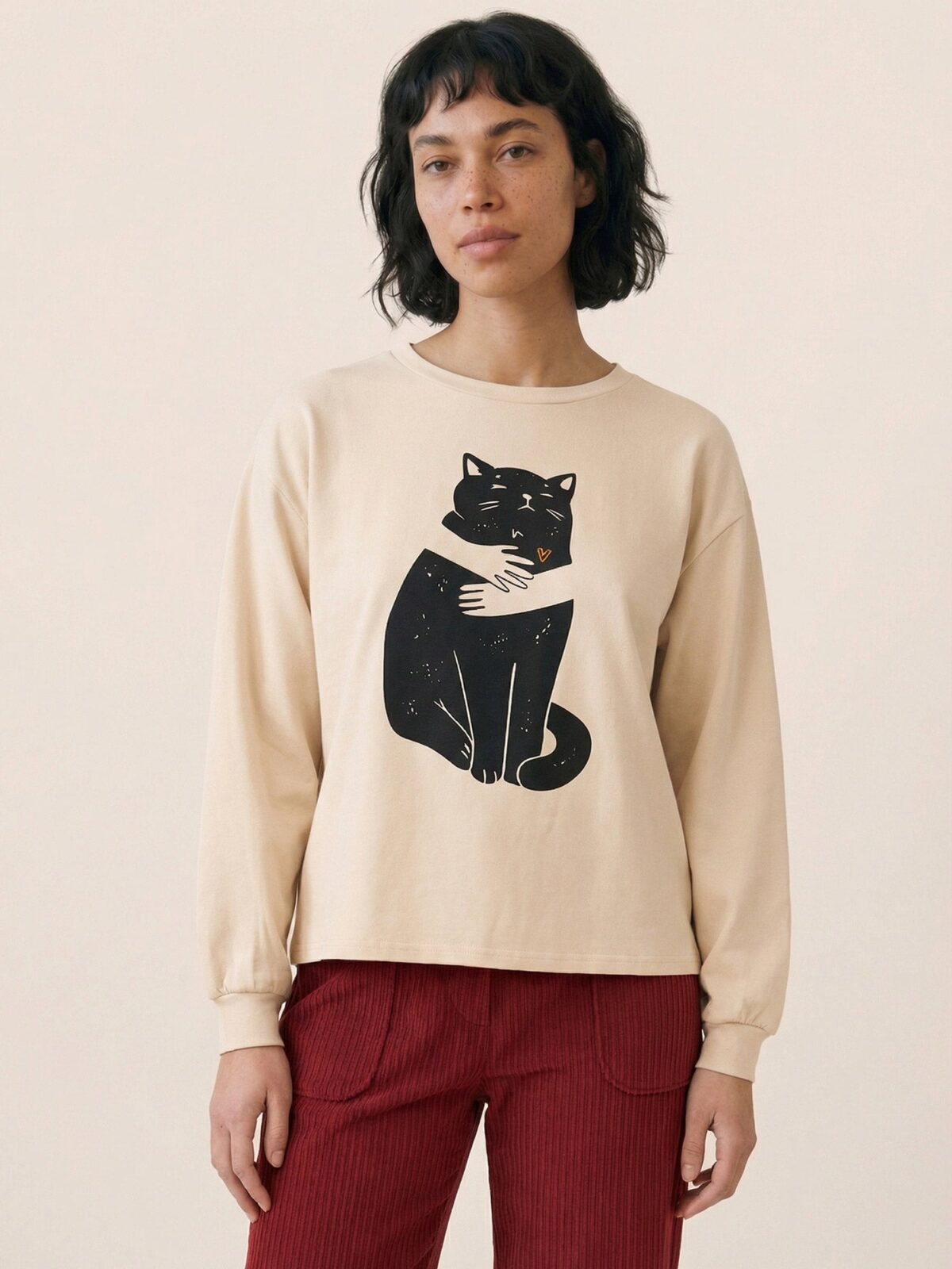 Camiseta beige con ilustración de un gato negro y corazón naranja de Pepaloves en Tiendas Via Vai Estepona