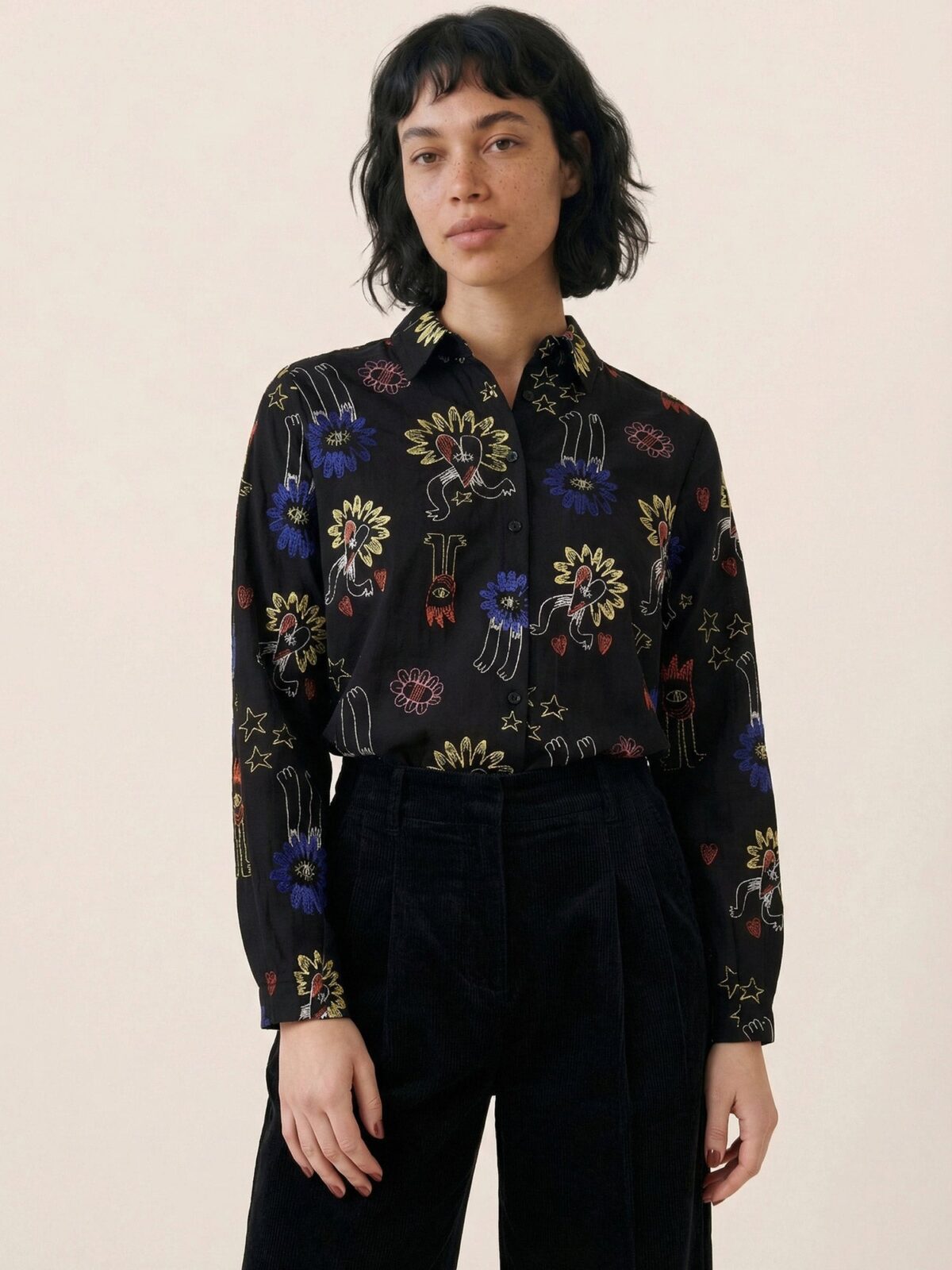 Camisa negra fluida con bordados multicolores de corazones alados y estrellas de Pepaloves en Tiendas Via Vai Estepona
